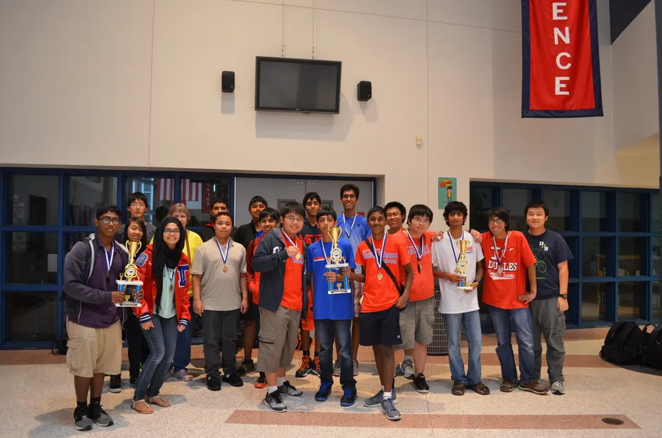 Club members holding trophies and medals after a programming contest.