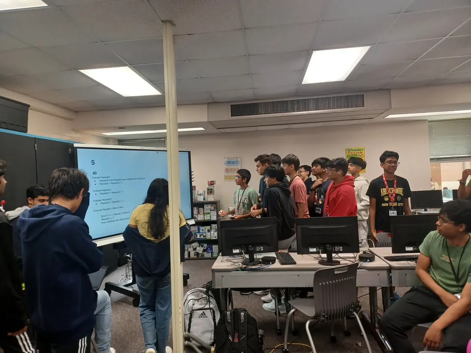 Members crowd around the screen to trace a recursion problem together.